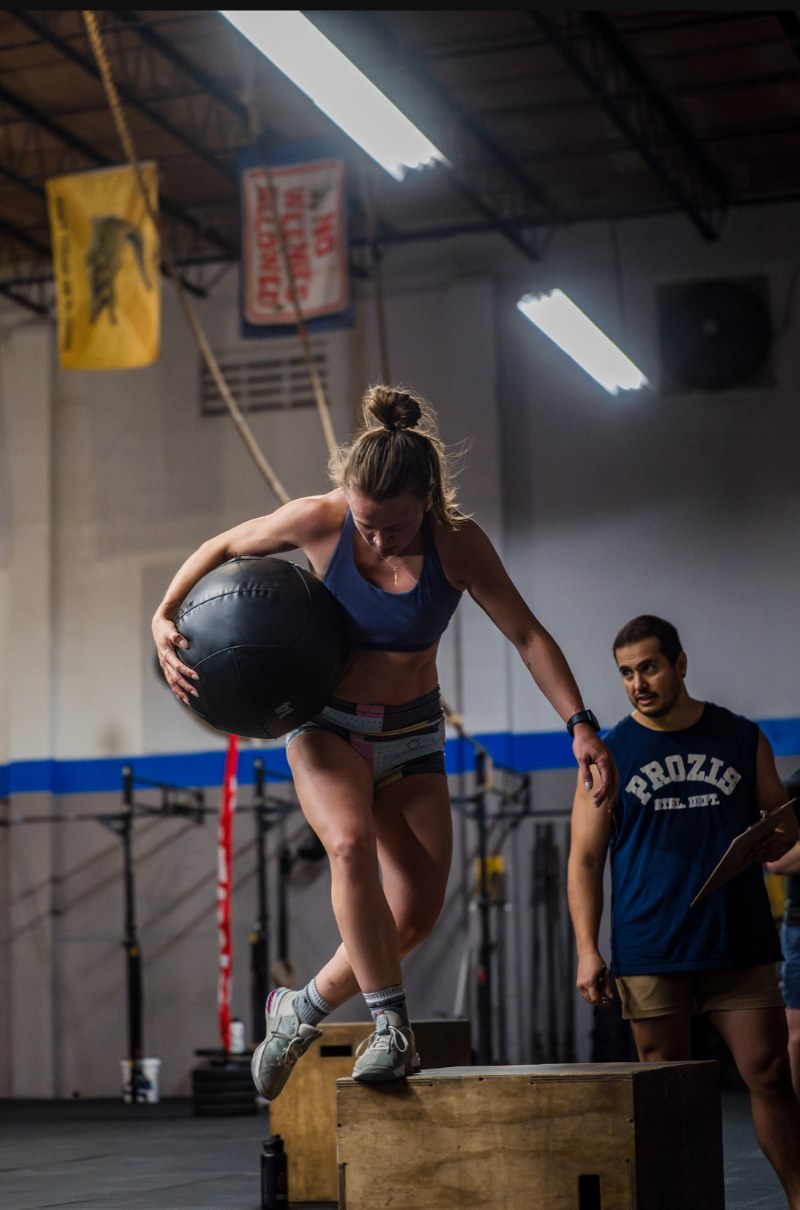 Jenna stepping off a box with a heavy medicine ball